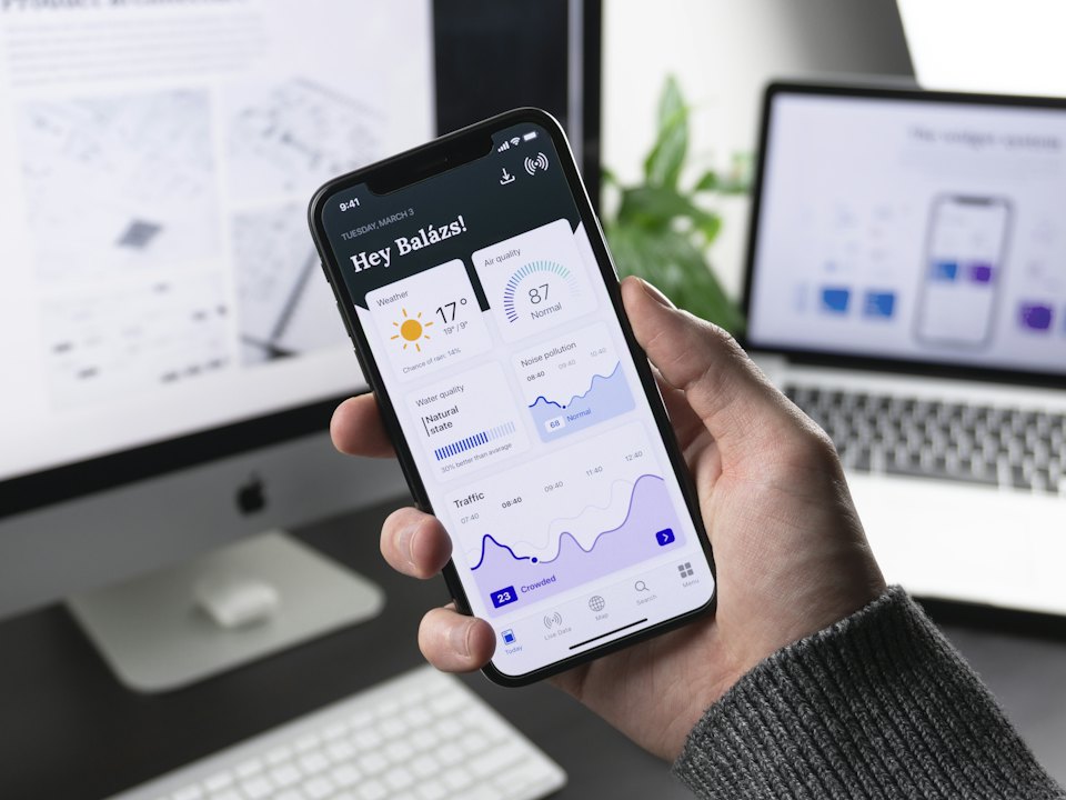 A hand holding a phone running a dashboard app